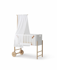 Bed with white sides and wooden details, equipped with a curtain and wheels for easy maneuverability.